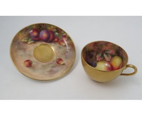 A Royal Worcester cabinet cup and saucer, the interior of the cup and the saucer hand painted with fruit to a mossy backgroun