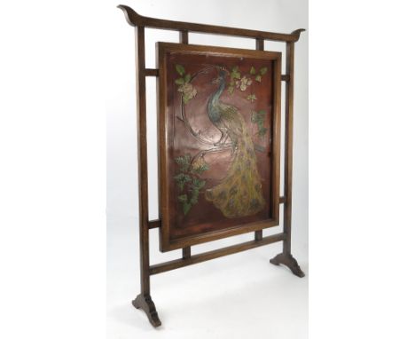 An oak framed Art Nouveau style fire screen, the embossed coloured leather panel decorated with a peacock on a branch, with p