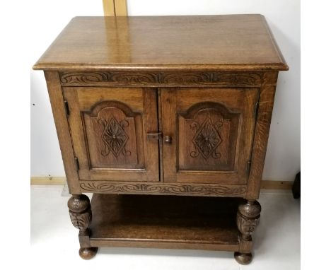 A reproduction oak court cupboard, with carved decoration, with shelf under, on bun feet. 77 cms in width, 92cms in height, 4