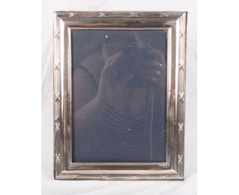 A modern silver faced photograph frame with reed and tie decorated border, 10" x 8"