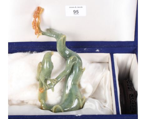 An early 20th Century Chinese jade carving of a bird on a blossoming prunus branch, with pierced and carved hardwood base and
