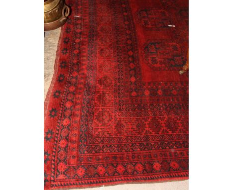 An Afghan carpet decorated twenty-one guls on a red ground and multi-bordered, 160" x 111" approx