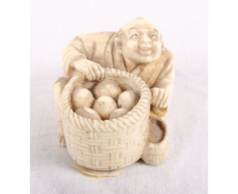 An ivory netsuke of a seated figure with a basket, signed