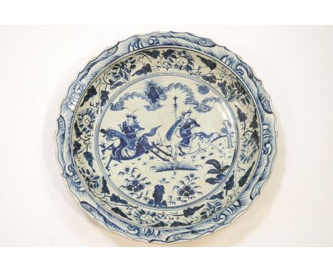 A substantial Chinese porcelain blue and white dish, the central panel depicting two warriors on horseback within a wide bord