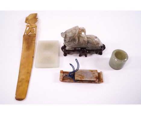 A Chinese jade carving of  recumbent beast, 8cm long, with wooden stand, a jade panel carved with a man, two further jade car
