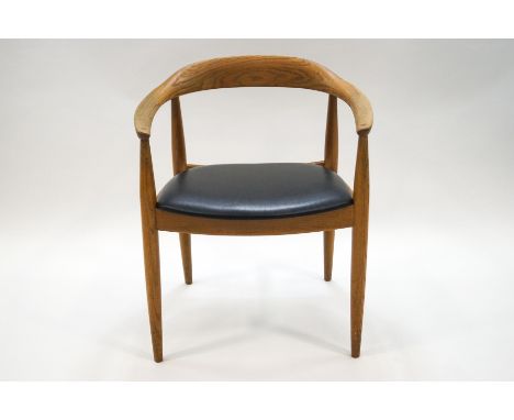 A 1960's Danish elm armchair with black leatherette seat, retailed by Eilerson, label to underside