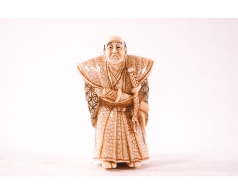 An early 20th century carved and part stained ivory netsuke, of a frowning warrior, signed to the underside, 5cm high 