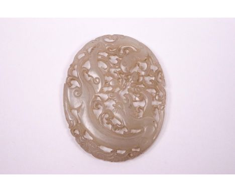 A Chinese mutton fat jade pieced oval panel, carved with a dragon, 6.5cm x 5.3cm, on wooden stand
