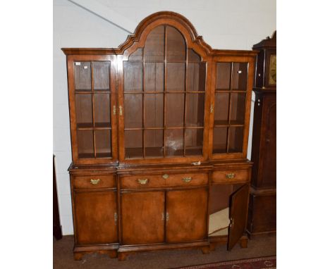 A Georgian style walnut breakfront bookcase, the central arched glazed door, flanked by two rectangular doors, on base with b