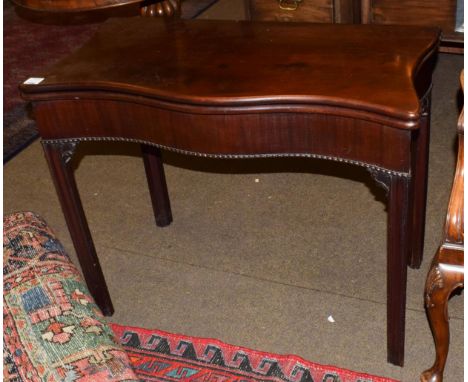 A George III mahogany serpentine shape foldover card table, circa 1780, enclosing a green baize lined interior above a plain 