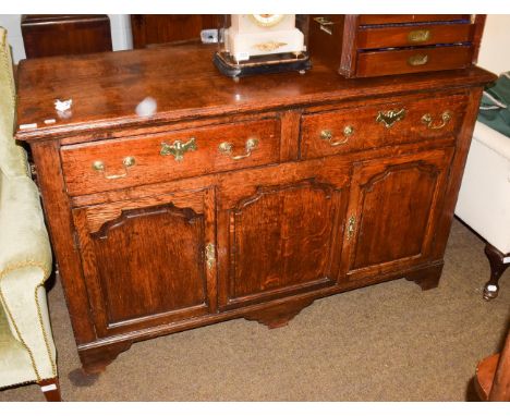 An 18th century oak enclosed low dresser, moulded rectangular top, two drawers, brass swan neck handles, two moulded panel do