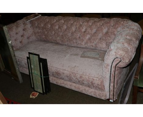 A Chesterfield style sofa, early 20th century, with ''Damask Rose'' button-back upholstery, mahogany bun feet to castors, 215