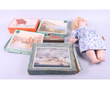 A metal trunk, containing various wooden puzzles of ships and landscapes, and a German porcelain faced doll