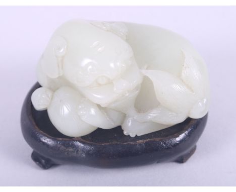 A carved jade Dog of Fo holding a ball, on hardwood stand, 2 1/2" highCondition: Fine no issues, stand is not original, jade 