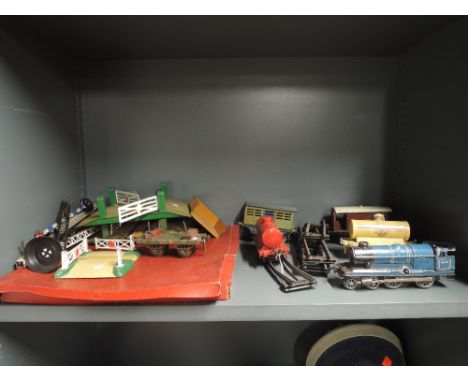 A shelf of 0 gauge including Chad Valley clockwork 4-4-0 loco, Hornby rolling stock and accessories etc