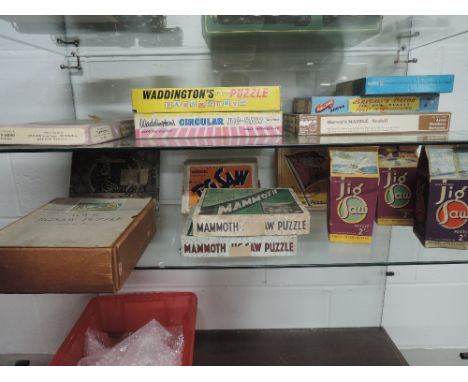Two shelves of 1930's and later wooden jigsaw puzzles including GWR, The Vikings landing at St Ives, Mammoth, The Boars Head 