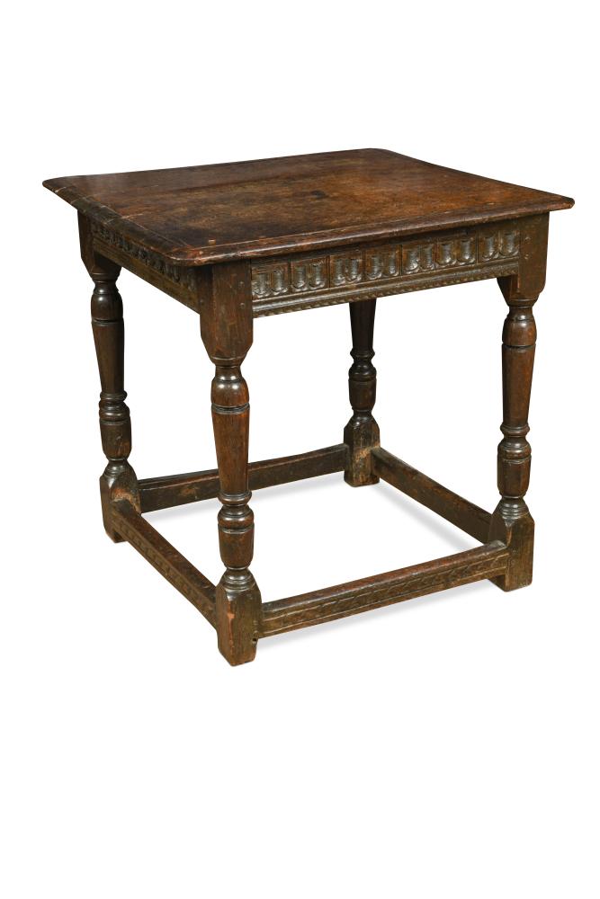 A 17th century oak square top table, with a carved frieze, on baluster