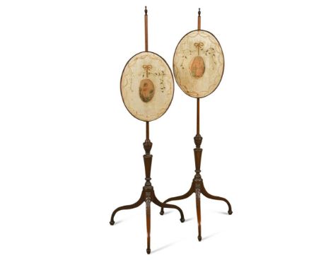 A pair of George III mahogany pole screens, with height adjustable oval panels, on husk carved tripod bases (2) 124cm (48in) 