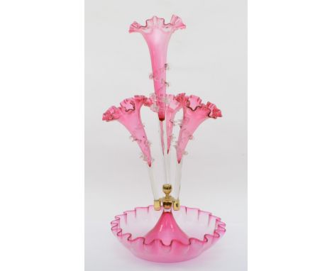 A late 19th/early 20th century cranberry glass three trumpet epergne with central trumpet, standig in a shaped glass dish,  4