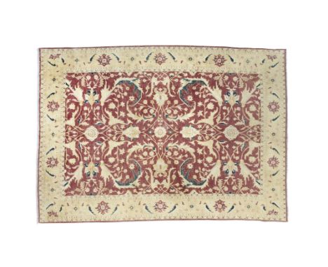 A ZIEGLER PATTERN WOOL CARPET, the red ground rectangular field woven with intertwined tendrils and flower heads, enclosed wi