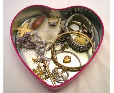 A heart shaped tin containing a quantity of costume jewellery to include a rolled gold bangle & hunting horn brooch.