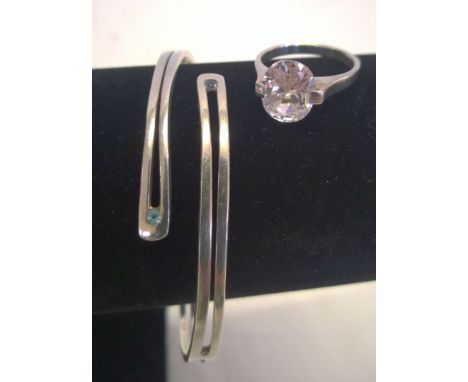 A 925 silver cross-over bangle set with 2 small blue topaz stones, together with a silver ring set with a large oval crystal,
