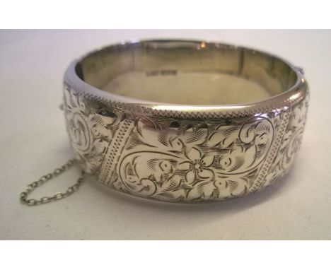 Hallmarked silver hinged bangle with safety chain.  Measures 2.5cm wide, weighs approx 40.5g.  Engraved to one half.  Very go