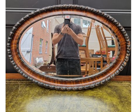 A 1920s mahogany and ebonized oval wall mirror, 62 x 87cm.&nbsp; 