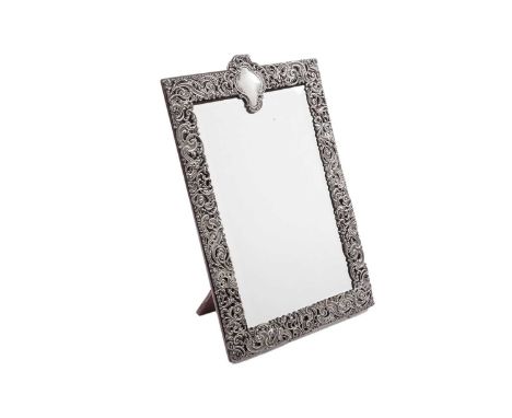 A late Victorian silver mounted dressing table mirror, rectangular with a bevelled glass plate, a wooden easel back and a pie