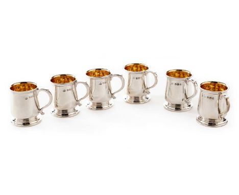 A George V cased set of six silver tot cups in the form of miniature mugs with gilt interiors, each numbered on the base, by 