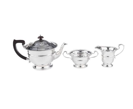 An Elizabeth II silver three-piece tea set, circular with lightly paralleled lower bodies, bead borders and scroll handles, b