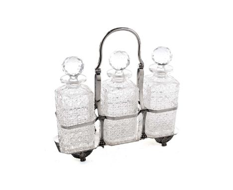 An electroplated art deco tantalus on winged paw feet, with a swing handle and three cut glass bottles with faceted globular 