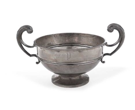 An Edwardian large silver two handled trophy cup of shallow circular form on a low spreading foot, with harp-shaped handles, 