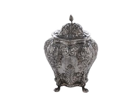 A late Victorian silver tea caddy of bombé form on four paw feet, with embossed decoration, a gilt interior and a domed cover