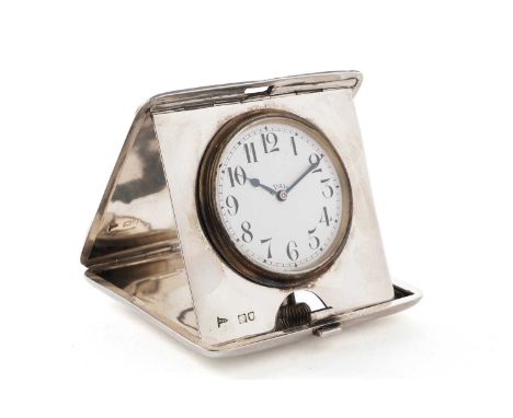 A George V silver travelling timepiece, with an engine-turned case, folding open to reveal a white enamelled dial with black 