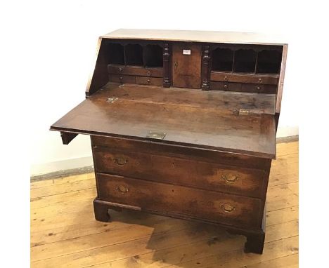 A George III oak fall front bureau, c.1790, the rectangular fall front enclosing a fitted interior of drawers and pigeon hole