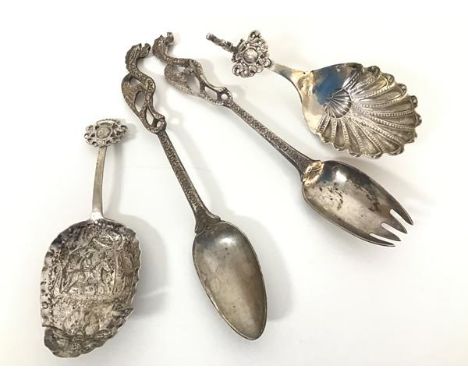A pair of Continental chased white metal short serving spoons, one with a cherub mounted handle, the other with a crest style