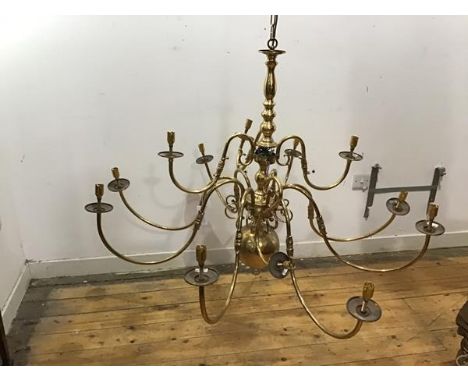 A brass pendant chandelier in the Dutch 18thc taste with eleven scrolling branches issuing from a baluster shaped stem, with 