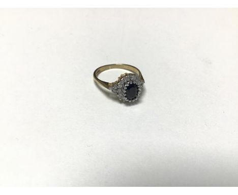 A sapphire and diamond cluster ring, the oval sapphire mounted in a claw setting with a surround of sixteen diamond chips, se