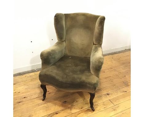 A late 19thc wing armchair, upholstered in a pale green velvet fabric, raised on cabriole legs terminating in ceramic castors