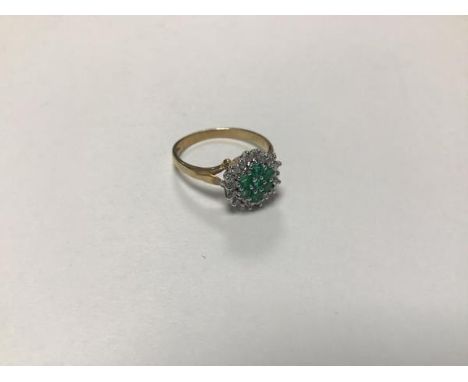 A 9ct gold emerald and diamond cluster ring with seven emeralds enclosed within a surround of nine diamonds (N) (2.3g)