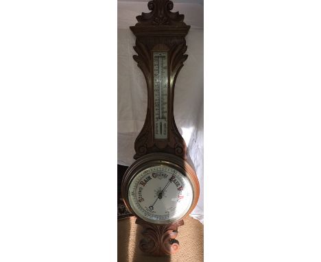 A light oak carved aneroid barometer, C1900 with white porcelain dial and thermometer scale. 