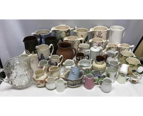 A large collection of ceramic jugs with 2 mugs and 1 glass jug.