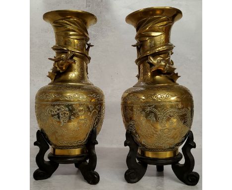 A pair of Chinese bronze slender necked temple vases, cast in relief with a dragon, chased stylised clouds, six character mar