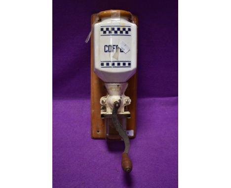 A vintage wall mounted ceramic crank handed coffee grinder with removable glass container to collect the ground coffee.
Mecha