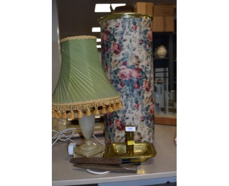 A brass candle stick holder, a table lamp with shade,an umbrella/stick or similar lidded storage vessel.