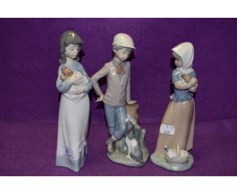 Three Lladro Nao figurines, two girls with puppies and a boy with dog at his feet.