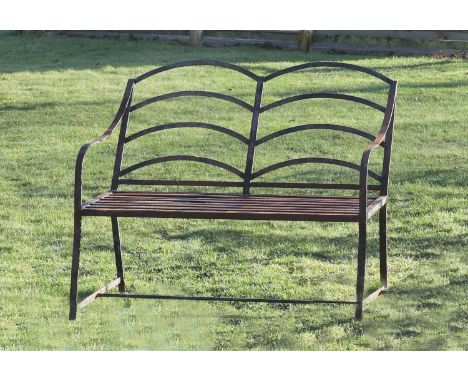 An estate made wrought iron two-seater garden bench, late 19th century, the back with arched slats, within sweeping arms and 