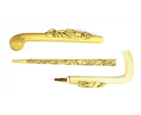 Three carved ivory parasol or walking stick handles , late 19th century, the first well carved with hunting trophies, includi