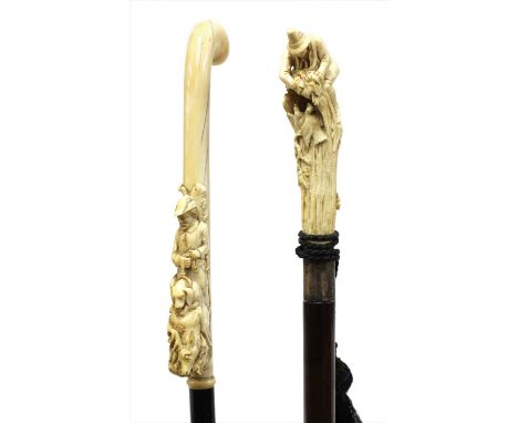 Two German or Austrian carved ivory walking sticks , late 19th century, the first with an Alpine huntsman removing eggs from 